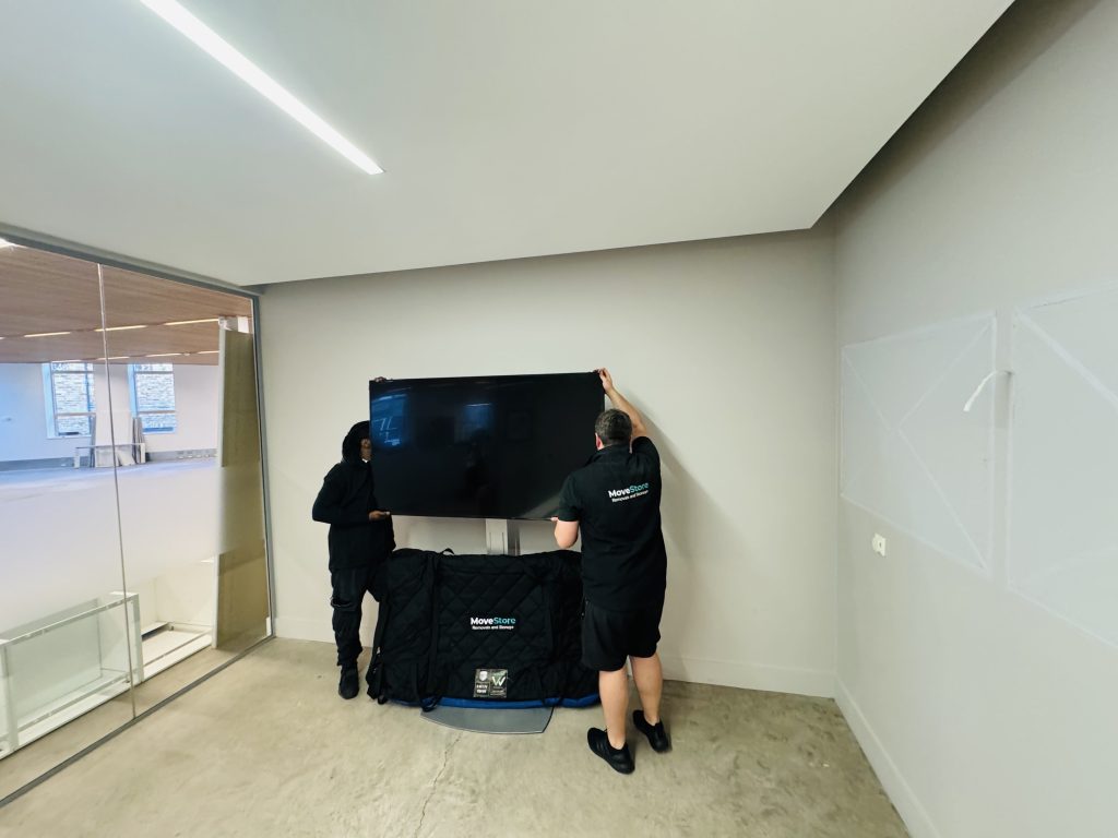 MoveStore movers packing a TV for an office relocation