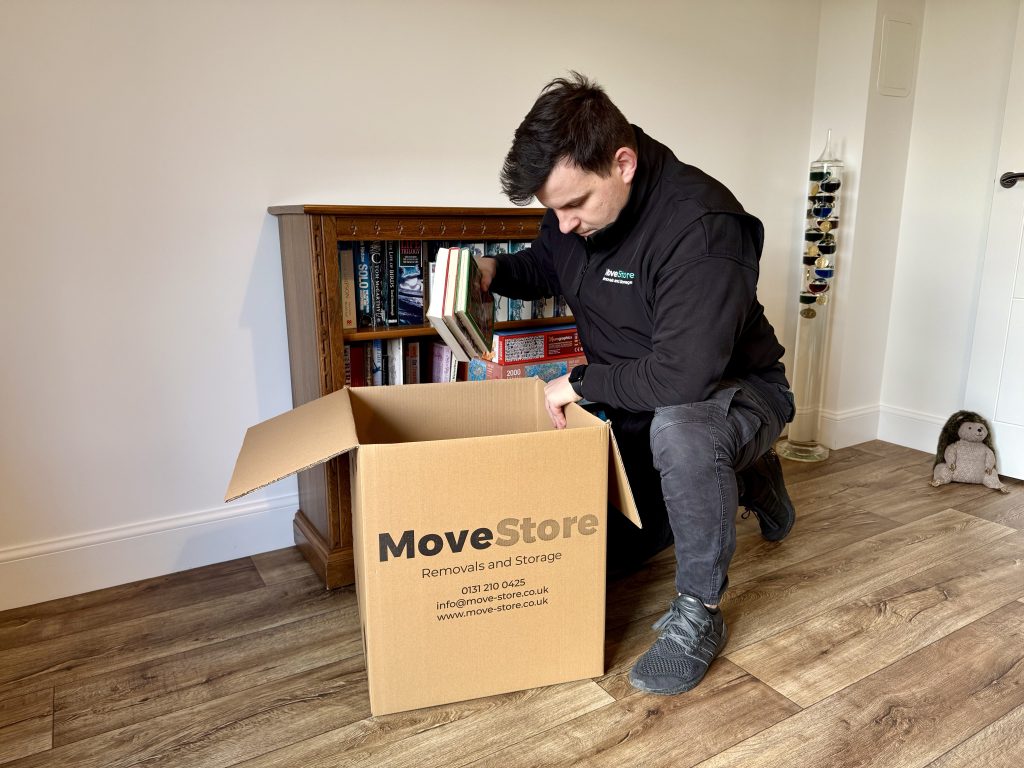 MoveStore packing service. A MoveStore mover packing books into a box.